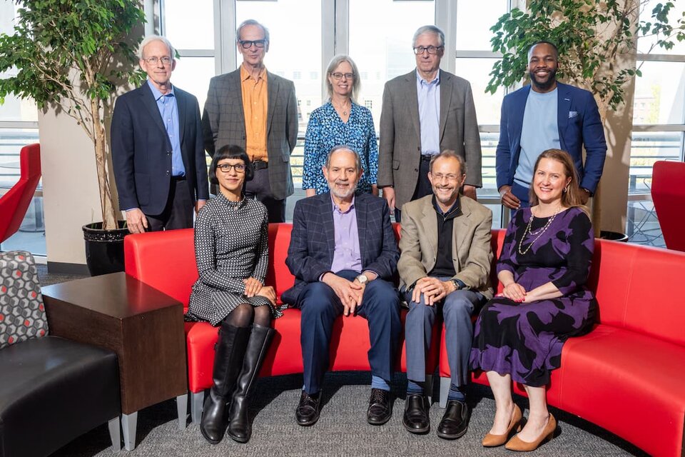 Speakers and organizers of 71st Nebraska Symposium on motivation sitting or standing behind a red couch